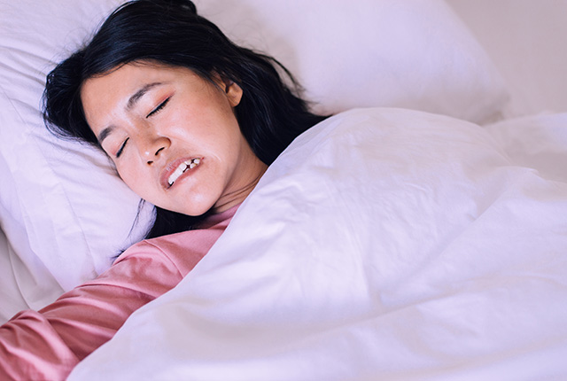 睡眠中に歯ぎしりをしている女性